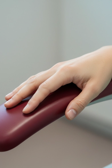 Hand einer Frau liegt entspannt auf der Lehne des Zahnarztstuhls (Makroaufnahme)