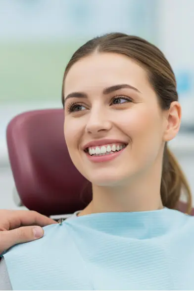 Frau im Zahnarztstuhl lächelt Zahnarzt Dr. Putzer in Hannover an